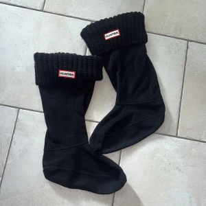Svarta fleece-strumpor från Hunter - Svarta strumpor från Hunter med ribbstickad kant och tydlig logga framtill. Tillverkade i mjuk fleece med en stickad överdel. Perfekta att ha i stövlar under kalla dagar.