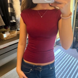 Mörkröd tight ärmlös topp - Säljer en mörkröd, tight och figurnära topp med ärmlös design och rund halsringning. Tröjan är i jätte bra skick då den bara är använd fåtal ggr💗