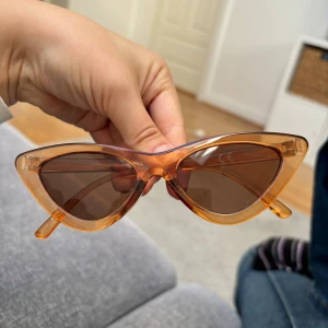 Retro cat eye solglasögon - Snygga cat eye solglasögon med transparent orange båge och bruna glas. Ramen är i plast och har en cool retrovibe som verkligen sticker ut. Vanliga i storleken. 