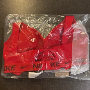 Röd sport- BH från Nike - Helt ny i originalförpackning. Sport-BH från Nike med mycket stöd. Indy Bra. Nyris: 579