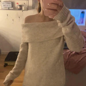 Offshoulder beige stickad tröja Gina Tricot - Supermysig beige stickad tröja från Gina Tricot med bred offshoulder-krage. Långärmad modell med ribbade muddar och nederkant. Perfekt för lager-på-lager och chill höst- och vinterstil.