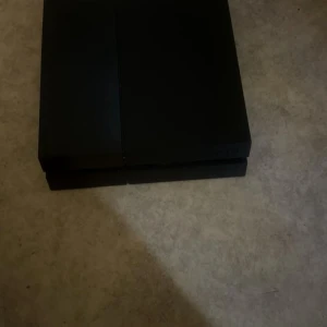 PlayStation 4 - Sony PlayStation 4 i svart färg. Konsolen ser ut att vara i gott skick med mindre tecken på normalt bruk. Perfekt för gaming och multimedia. Alla portar och ventilationsgaller syns tydligt. Inga större repor eller skador synliga på bilderna.