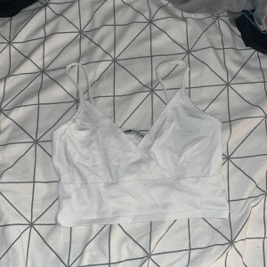 Vit omlott linnetopp från FB Sister - Säljer en vit omlott linnetopp från FB Sister i storlek XS. Toppen har smala axelband, omlott-skärning framtill och är croppad. Perfekt för varma dagar och enkel att matcha med jeans eller kjol.