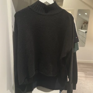 Svart stickad polotröja Gina Tricot - Mysig svart stickad polotröja från Gina Tricot med ribbad hög krage och långa ärmar. Perfekt för lager-på-lager och chill höst- och vinterstil. Enkel att matcha med jeans eller kjol för en clean look.