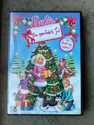 Barbie En perfekt jul dvd - Barbie En Perfekt Jul på DVD. Följ med Barbie och hennes systrar Skipper, Stacie och Chelsea när deras julledighet oväntat förvandlas till ett spännande äventyr.  Finns på språk: Svenska, Engelska, Finska  OBS!! skivorna är begagnade så det kan förekomma repor/hairlines på skivorna, men då jag kollar igenom alla filmer jag säljer garanterar jag att alla funkar felfritt om inget annat står! :)