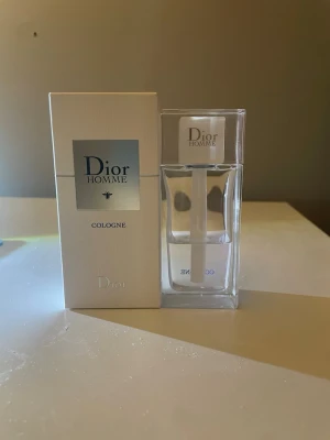 Dior Homme Cologne Eau de Toilette - Fräsch och stilren herrparfym från Dior, Homme Cologne. Flaskan är transparent med vit och silverfärgad detalj och har en modern, minimalistisk design. Förpackningen är vit med silverdetaljer och tydlig Dior-logga. Perfekt för dig som gillar exklusiva dofter. 75 ml 40ml kvar