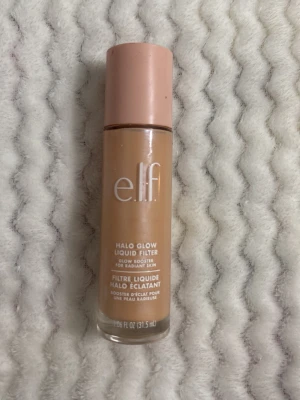 e.l.f. Halo Glow Liquid Filter foundation - Säljer en e.l.f. Halo Glow Liquid Filter foundation i flytande form. FÄRG ”FAIR” Kommer i en glasflaska med rosa lock och stor applikator. Färgen är medium beige med varm underton, perfekt för en naturlig glow och jämn hudton. Har använt den tre gånger nästa ny
