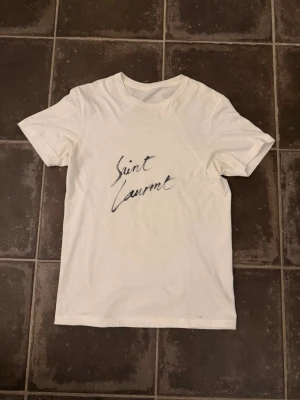 Saint Laurent t shirt  - Riktigt fet och eftertraktad saint Laurent t shirt i storlek S! Helt nytt skick! Lite osäker på äktheten eftersom lappen i nacken saknas så därför är priset just nu på 499kr nypris runt 3000kr! Tveka inte med att ställa frågor! 