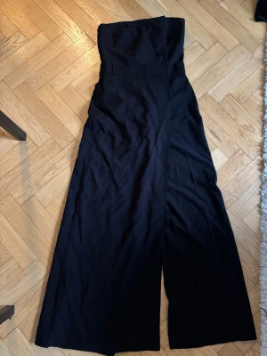 Svart byxdress med knappar - Stilren svart byxdress med hög midja och vida ben. 