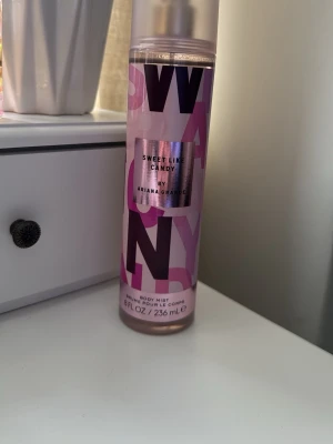 Sweet Like Candy Body Mist Ariana Grande - Säljer en Sweet Like Candy body mist från Ariana Grande. Flaskan är cylinderformad i plast med rosa och lila text och har ett genomskinligt lock. Innehåller 236 ml och doften är söt och fruktig, perfekt för dig som gillar lätta och ungdomliga parfymer.