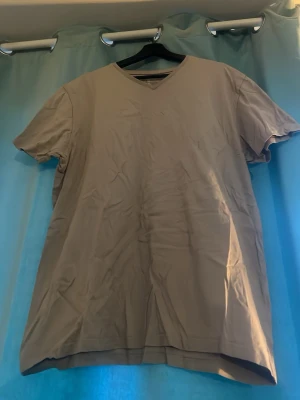 Beige v-ringad t-shirt - En enkel och stilren beige t-shirt med v-ringning och korta ärmar. Perfekt basplagg i garderoben! Passar till många olika outfits och är lätt att matcha.