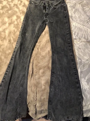 Grå bootcut jeans från Perfect Jeans - Säljer ett par grå bootcut jeans från Perfect Jeans i storlek 32. Jeansen har en riktigt snygg utsvängd passform och klassisk femficksdesign. Materialet är jeans med en tvättad look som ger en cool vintagekänsla.