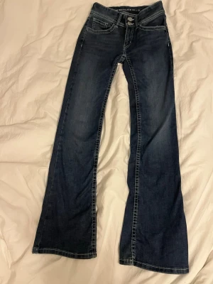  bootcut lågmidjade jeans mörkblå - Jättefina lågmidjade bootcutjeans i mörkblå tvätt och med vita sömmar. Jeansen har även broderade bakfickor och dubbla knappar fram på. De är i st. XS och med längden 32. Jeansen är nästan helt oandvända och är i nyskick💕det är bara att höra av sig om mer information! (Inga returer och skickar så fort jag kan)