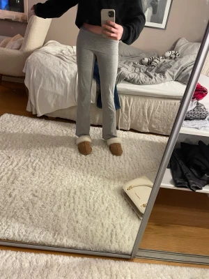Grå mjukisbyxor med bootcut - Säljer ett par grå mjukisbyxor med bootcut och låg midja. Byxorna är i mjukt bomullsmaterial och har en skön, loose passform som sitter snyggt över höfterna. Perfekta för chill dagar hemma eller när du vill vara bekväm men ändå se stilren ut.