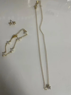 Guldiga blomörhängen med stenar - Säljer ett par söta örhängen i guldton med blommor formade av gnistrande vita stenar. Örhängena har en elegant och feminin look, perfekta för dig som gillar detaljer och bling. Materialet ser ut att vara metall med glittrande stenar i varje blomblad.