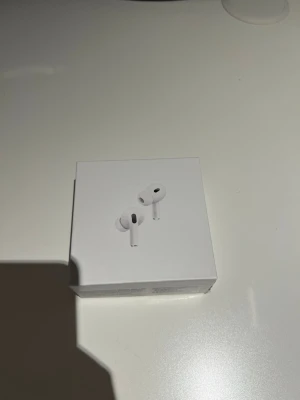 Apple AirPods Pro trådlösa hörlurar - Säljer ett par vita Apple AirPods Pro med laddningsetui och extra silikonpluggar. Snygg och kompakt design i plast, perfekt för dig som vill ha grymt ljud och brusreducering. Allt kommer i originalförpackning.