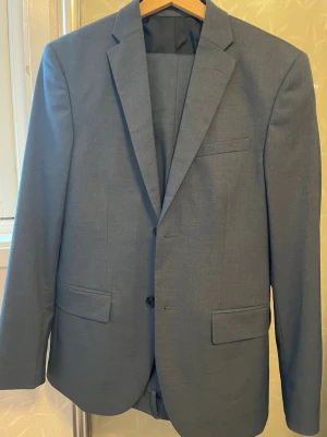  klassisk kostymkavaj - Kavaj med tillhörande byxor. I en fin blå. De är en slim fit model i stl 46. Endast använd en gång, och tvättad en gång. Köpt på H&M 