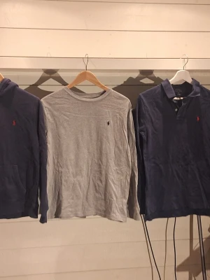 Grå långärmad tröja från Ralph Lauren - Snygg grå långärmad tröja från Ralph Lauren med den klassiska lilla broderade loggan på bröstet. Storleken är L 14-16. Tröjan har rund halsringning och är tillverkad i mjuk bomull, perfekt för en avslappnad och stilren look. Gå in på annonsen för att se hela bilden!