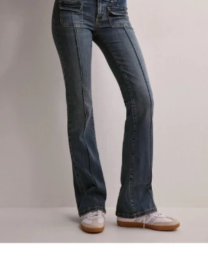 Blå bootcut jeans från Nelly - Snygga blå bootcut jeans från Nelly med dubbla knappar i midjan och markerade sömmar längs benen. Lite slitna längst ner på benen men inget som syns ❤️