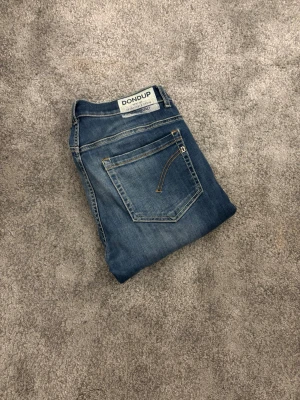 Dondup George - Snygga blåa Dondups i modellen George. Jeansen är bekväma och passar perfekt till en stilren och snygg look! Jeansen är i strl 34 men skulle säga att de sitter mer som 33! Jeansen har använts ganska mycket men är fortfarande i mycket bra skick! Skriv vid minsta fundering eller önskemål av fler bilder💯!