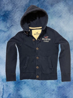 Vintage Hollister Cardigan Med Knappar - Säljer denna otroliga sällsynta och feta Hollister cardigan med knappar | Mycket bra Skick | Längd ≈ 65cm, Bredd armhåla - armhåla ≈51 cm | Modell 175, 68 kg | PRIS KAN DISKUTERAS