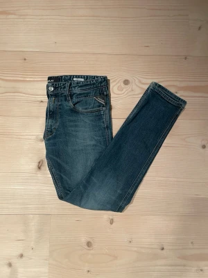 Blå Replay Anbass  jeans med skinny passform - Snygga blå jeans från Replay med klassisk femficksdesign och skinny passform. Jeansen har en lätt tvättad look och detaljerade sömmar. Perfekta för dig som vill ha ett par stilrena och bekväma jeans i garderoben.