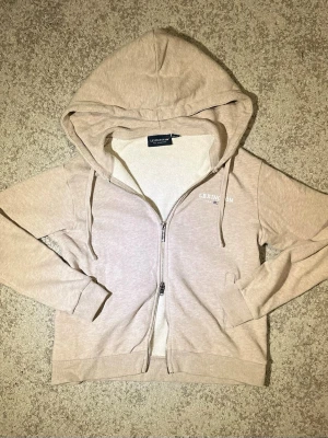 Lexington zip hoodie - Hej! Säljer en stilren beige zip hoodie från Lexington. Tröjan har tvåvägsblixtlås som ger en unik touch. Tillverkad i 100 % bomull och i mycket gott skick utan några skador då den knappt använts. Köpt för 899 kr. Fler bilder finns – bara att höra av sig vid minsta fundering!!
