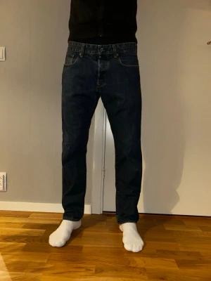 Mörkblå jeans från G-Star RAW - Snygga mörkblå jeans från G-Star RAW med klassisk femficksdesign och raka ben. Jeansen har en normal passform och är tillverkade i slitstarkt denimtyg. Perfekta för dig som gillar en stilren och enkel look.34/32