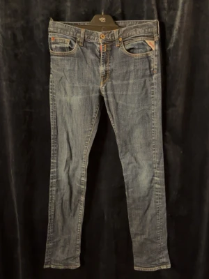 Replay jeans - Snygga blå jeans från Replay. Klassisk femficksmodell med orange sömmar och knappgylf. Jeansen har en något tvättad look och är tillverkade i slitstarkt denimtyg. Skriv för frågor (storlek 166cm) (rare byxor i limited edition)