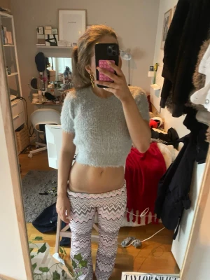 Ljusgrå fluffig cropped stickad tröja - Supermjuk och fluffig ljusgrå stickad tröja från Zara. Modellen är cropped med korta ärmar och rund halsringning. Perfekt för lager-på-lager och ger en trendig look. Materialet är lurvigt och känns riktigt cozy.