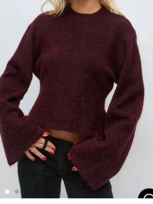 Vinröd stickad tröja med vida ärmar - Trendig vinröd stickad tröja med croppad passform och extra vida ärmar. Tröjan är från gina och använd 2 ggr köpt i oktober den är i storlek S 14+