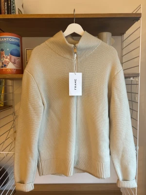 Beige stickad zip-tröja från FRAME. Runt 6000kr i nypris - Snygg beige stickad tröja från FRAME med hög krage och zip-dragkedja framtill. Tröjan har ribbade muddar vid ärmslut och nederkant, samt en relaxed passform. Perfekt för lager-på-lager under kyliga dagar. Storlek S men skulle säga att den sitter mer åt M. Grymt bra skick. Sitter lite baggy. Ny pris runt 5000-6000kr  kan tänka mig att gå ner lite i pris vid en snabb affär :) 