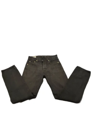 Svarta Levi's 501 jeans W30 L32 - Klassiska svarta Levi's 501 jeans med raka ben och knappgylf. Jeansen har fem fickor och detaljer i mässing. Perfekta för dig som gillar tidlös stil och vill ha ett par jeans som funkar till allt.