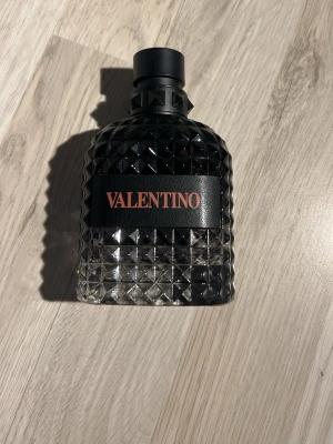 Valentino parfym svart glasflaska - Snygg parfym från Valentino i en mörk, diamantmönstrad glasflaska med svart lock. Flaskan har en lyxig känsla och Valentino-loggan i rött på svart band framtill. Perfekt för dig som gillar exklusiva dofter och stilren design. 0 ml 