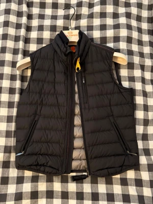 Svart dunväst från Parajumpers - Snygg svart dunväst från Parajumpers med gul detalj vid kragen och grått foder. Västen har två dragkedjefickor fram och en bröstficka med dragkedja. Priset kan diskuteras 😊👍