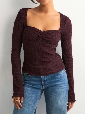 Mörkröd långärmad topp - Trendig mörkröd topp med lång ärm och smockad, rynkad struktur. Toppen har en snygg v-ringad urringning och figurnära passform som framhäver siluetten. Perfekt att styla med jeans eller kjol för en cool look. Aldrig använd med prislapp kvar