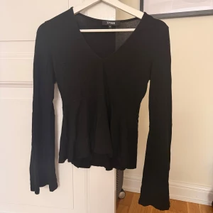 Svart långärmad topp  - Svart långärmad topp som jag tror att jag köpte på New yorker i storlek XS. Modellen har v-ringning och utsvängda ärmar som ger en snygg siluett. Tunt och mjukt material, perfekt att styla med jeans eller kjol. Enkel men ändå trendig design.