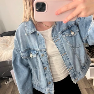 Oversized  jeansjacka Zara - Säljer en oversized ljusblå jeansjacka från Zara med klassisk krage och silverfärgade knappar. Jackan har två bröstfickor med lock och knapp, samt en avslappnad passform som ger en cool vibe. Perfekt att slänga över en t-shirt för en chill look.