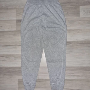 Grå mjukisbyxor från R teens - Snygga grå mjukisbyxor från R teens med elastisk midja och ribbade muddar vid bensluten. Byxorna har en relaxed passform och är tillverkade i mjukt bomullsmaterial som är perfekt för chill dagar. Enkla att matcha med hoodies eller t-shirts.