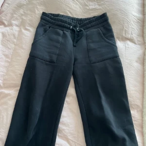 Svarta mjukisbyxor med snörning - Svarta mjukisbyxor med bred resår i midjan och snörning framtill. Byxorna har två stora fickor framtill och raka ben. Perfekta för en avslappnad och chill stil.