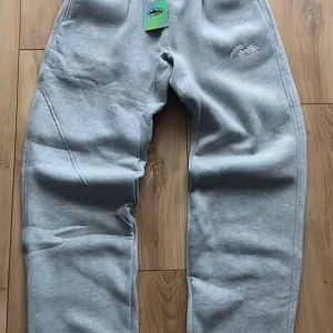 Grå mjukisbyxor från Corteiz - Snygga och stilrena gråa byxor från Corteiz i storlek S – perfekta för både vardag och streetwear!  Rak passform som ger en avslappnad look, med resår i midjan för skön komfort. Broderad logga på sidan som detalj. Byxorna är i helt nytt skick. Pris kan diskuteras vid snabb köp.  Passar dig som gillar en trendig men samtidigt enkel stil. Möts upp eller skickas – du väljer! Skicka PM vid frågor 💬