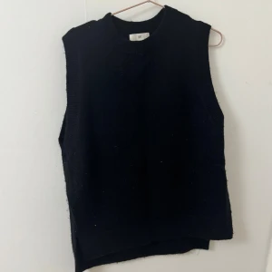 Svart stickad väst från H&M - En svart stickad väst från H&M med rund halsringning och slitsar i sidorna. Västen har en loose passform och är perfekt att slänga över en skjorta, xs i storlek men passar säkert en s oxå då den är pösig, använd endast en gång, materialet är åt det noppriga hållet, de liksom så tröjan är. 