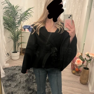 Svart pocho kappa med bälte - Säljer en svart pocho kappa och knytbälte i midjan. Väldigt skön och fin, bra mjukt material. Perfekt för dig som vill ha en stilren och cool look till höst och vinter.