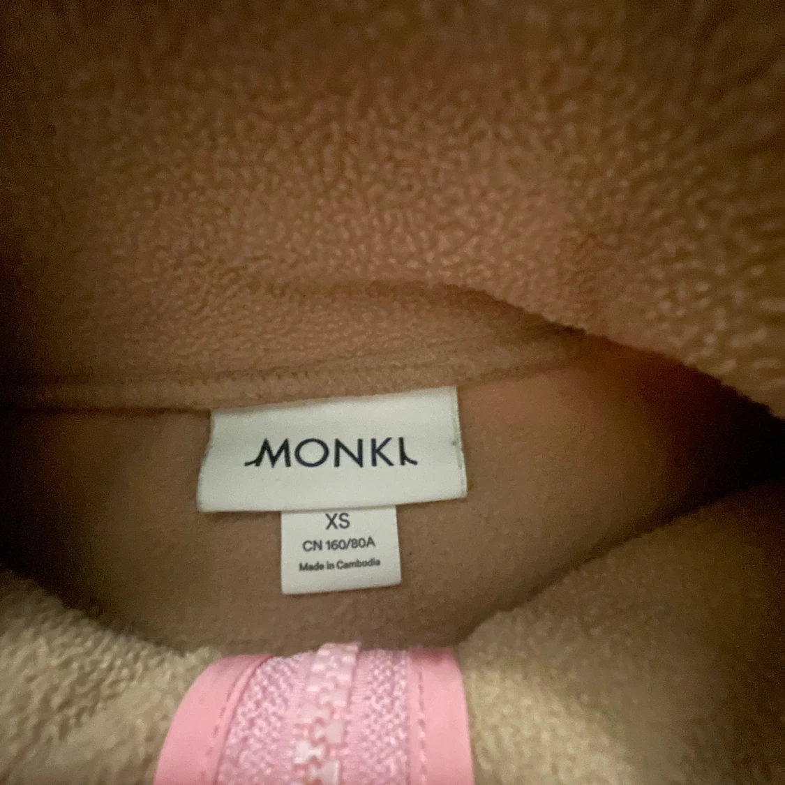 Beige fleece med rosa detaljer från Monki