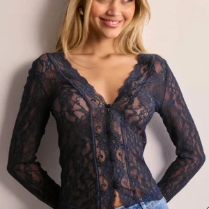 Mörkblå spetsblus med v-ringning - Säljer en mörkblå spetsblus från Nelly med v-ringning och långa ärmar. Blusen har dekorativa knappar framtill och är figurnära med fina spetsdetaljer. Storlek xs, använd två gånger. Pris kan diskuteras 