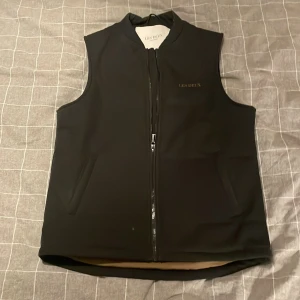 Les Deux - Säljer den här stilrena västen från Les Deux. Vind och vatten tålig med en svart färg på utsidan och brun på in sidan. Den är i storlek S men passar även M. Det är bara och skriva om du har några frågor.