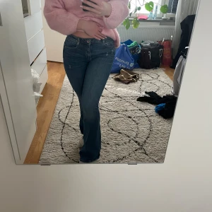 Blå bootcut jeans från Zara - Säljer ett par blå bootcut jeans från Zara i storlek 34. Jeansen har klassisk femficksdesign, låg midja och är tillverkade i stretchig denim. Snygg passform med utsvängda ben och diskreta slitningar för en cool look. Jag är 163cm lång och jeansen är lite för långa på mig.