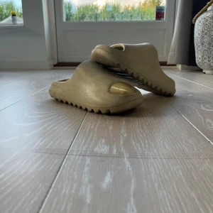Yeezy tofflor storlek 40 - Dessa tofflor är i färgen beige och är storlek 40, har tecken på användning och pris kan diskuteras.