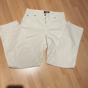 Vita byxor från Dickies W28 - Säljer ett par vita byxor från Dickies i storlek W28. Byxorna har raka ben, flera fickor både fram och bak samt klassisk Dickies-logga på bakfickan. Tillverkade i kraftig bomull för en cool och avslappnad look.