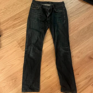 Mörkblå jeans från J.Lindeberg - Snygga mörkblå jeans från J.Lindeberg med klassisk femficksdesign, kontrastsömmar och diskret logga på myntfickan. Jeansen har rak passform och är tillverkade i slitstarkt denimtyg. Perfekta för dig som gillar stilrena och tidlösa jeans.